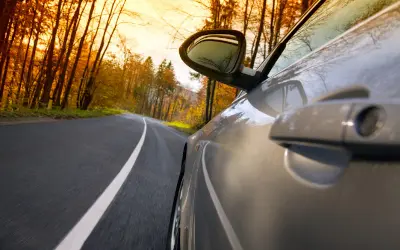 Bil på en väg genom en höstskog